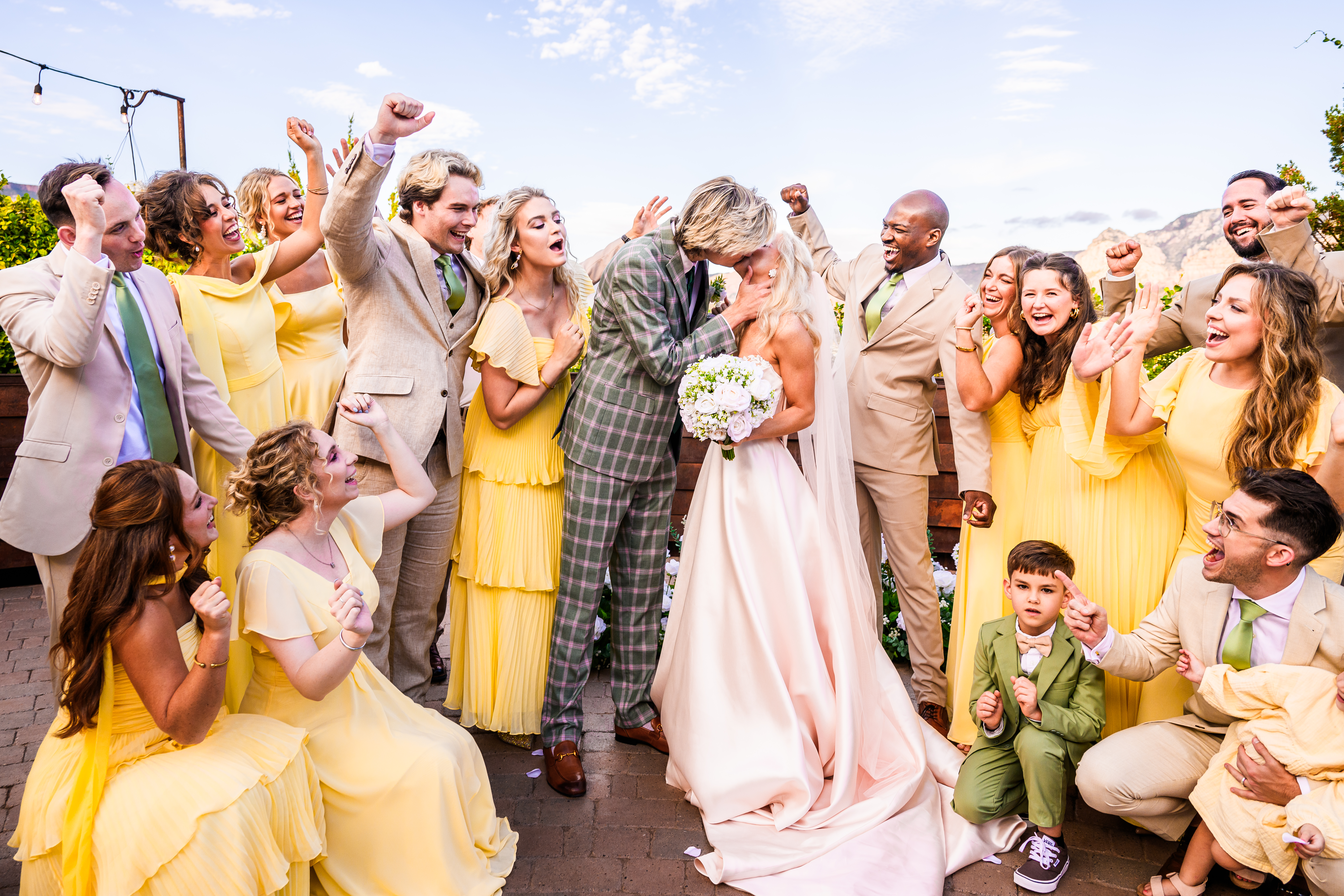 bride and groom surrounded by wedding party cheering for them as they kiss, at Agave of Sedona