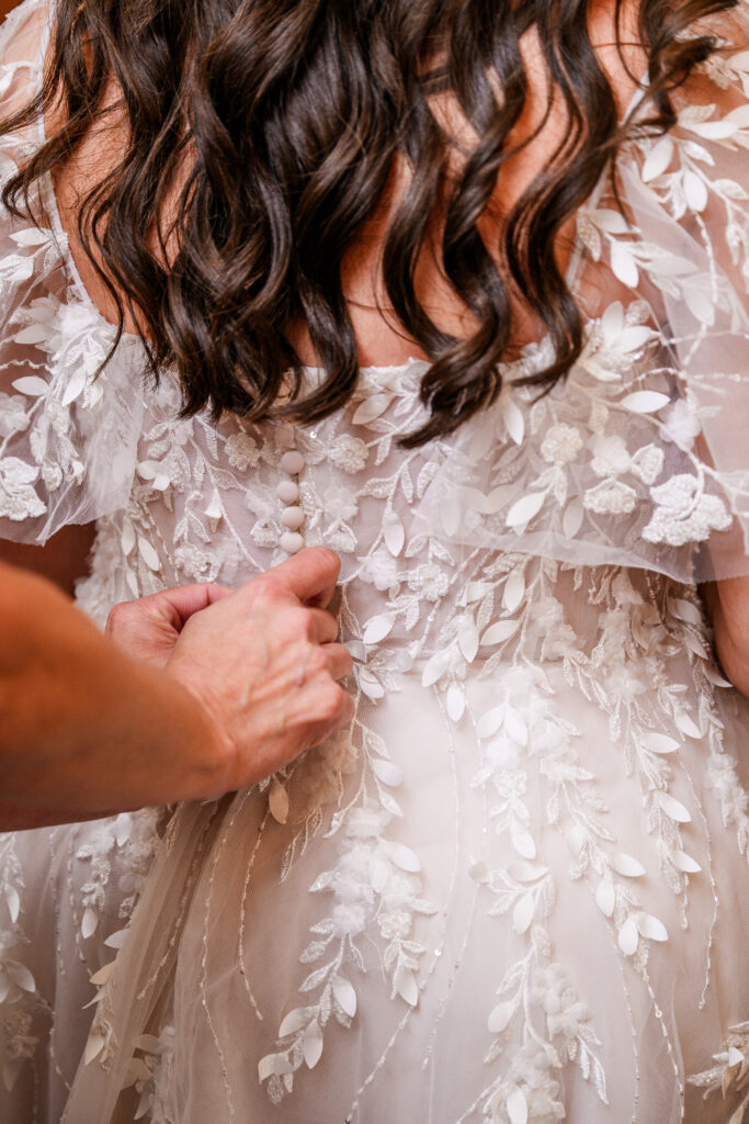 close up of mother zipping up bride wedding dress in bridal suite at the Windmill House in Chino Valley Arizona