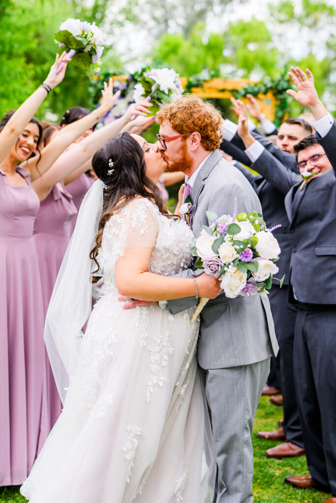 bridal party cheering for bride and groom kiss with tree background at the Windmill House Prescott Chino Valley Arizona