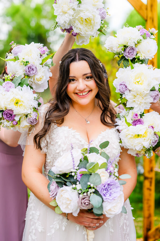 bride looking at camera with bridesmaids holding bouquets around bride with tree background at the Windmill House Prescott Chino Valley Arizona